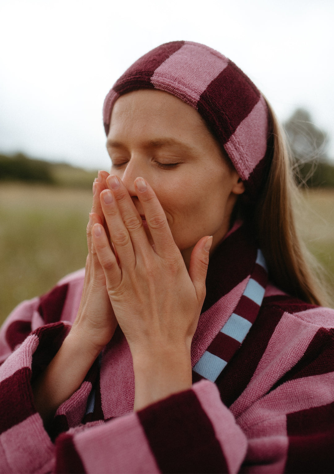 Woman outdoors wearing TBCo Terry Cotton Hair Tie in Burgundy Stripe paired with matching terry cotton robe in soft fabric