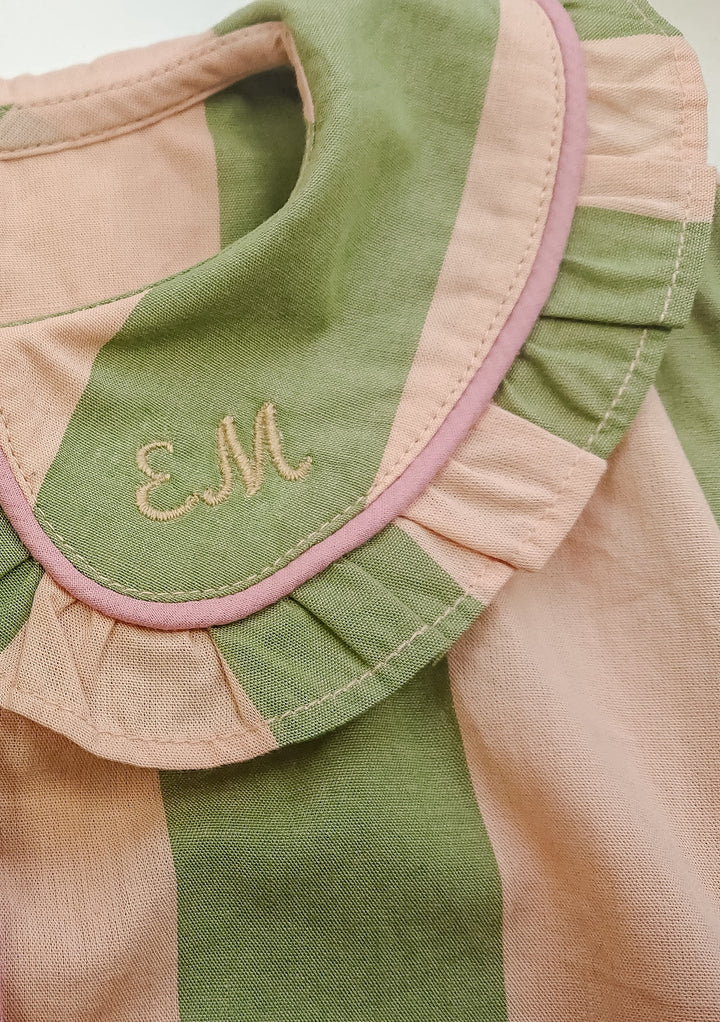 Close-up of TBCo Cotton Kids Pyjamas in Green Stripe featuring ruffled collar and monogram embroidery detail