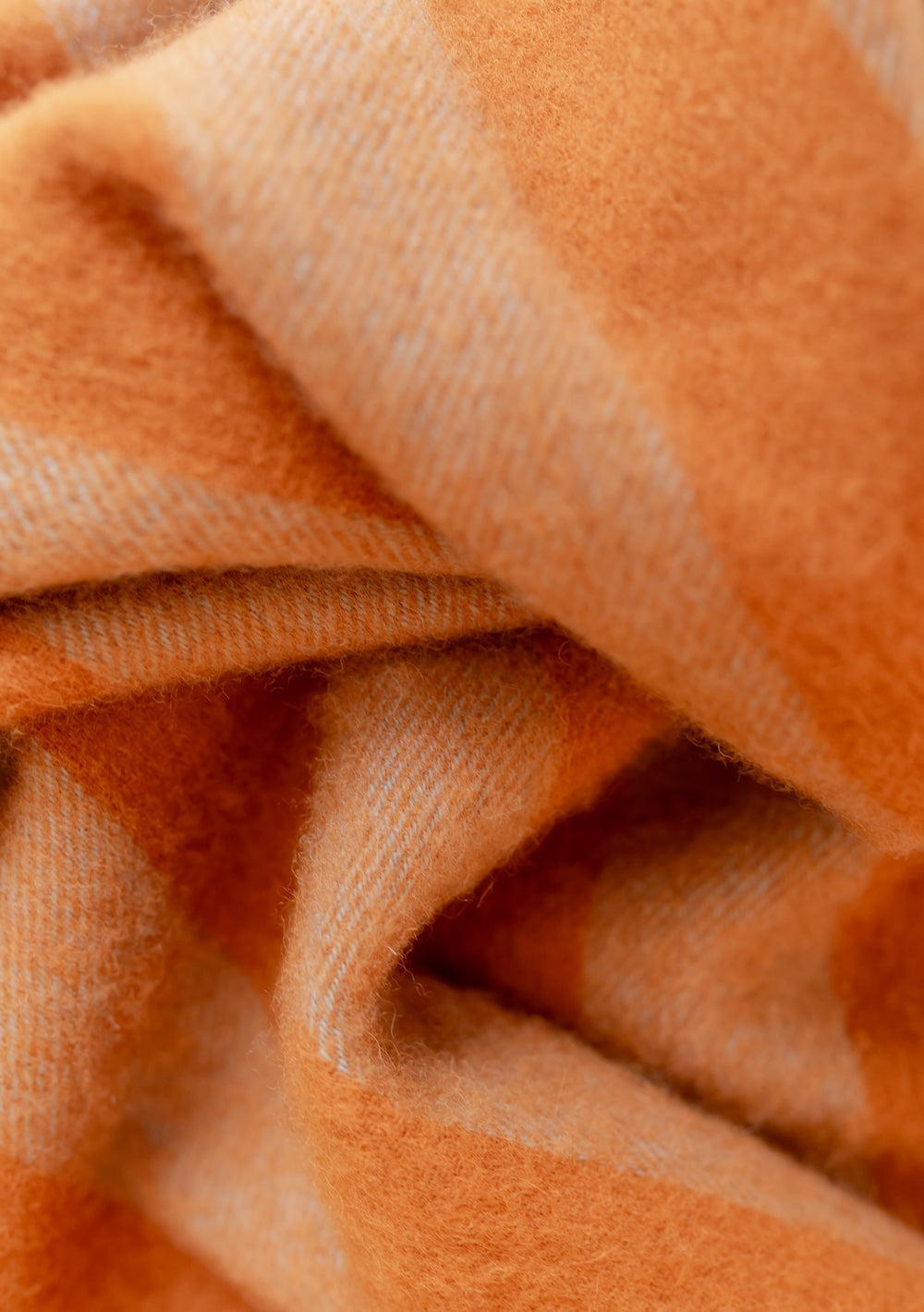 Close-up of soft lambswool fabric in pumpkin colour from TBCo's Lambswool Baby Blanket in Pumpkin & Blue Stripe.