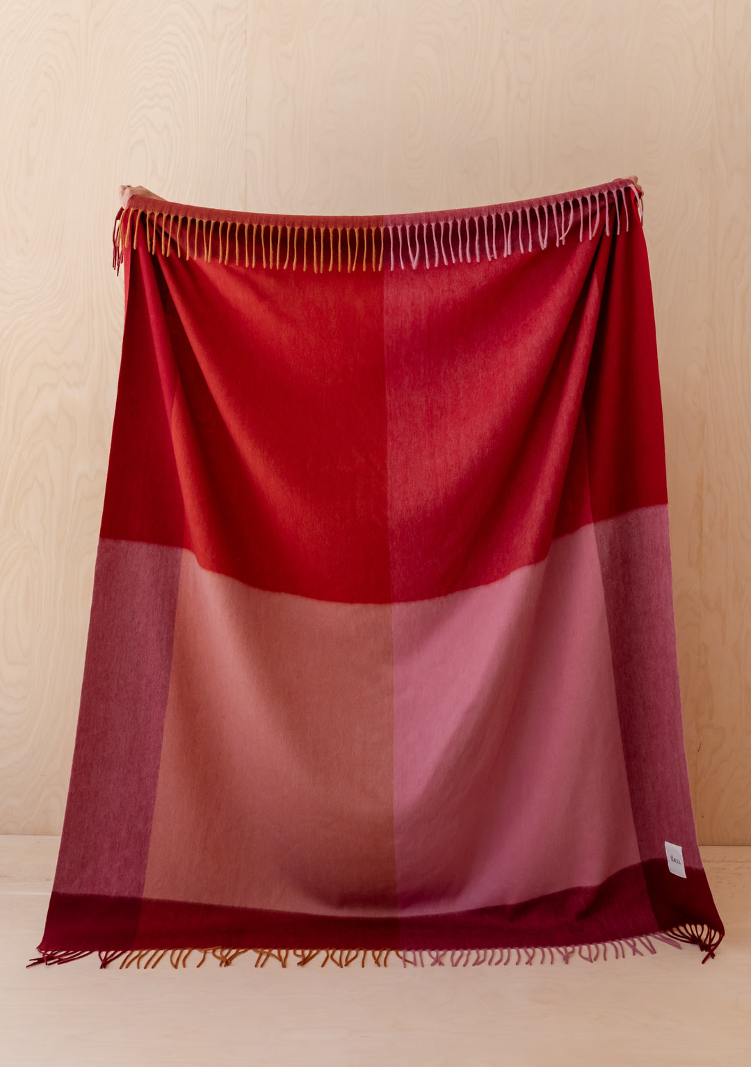 TBCo Lambswool Blanket in Berry Frame Check with fringed edges showcases soft red and pink tones in a classic design.