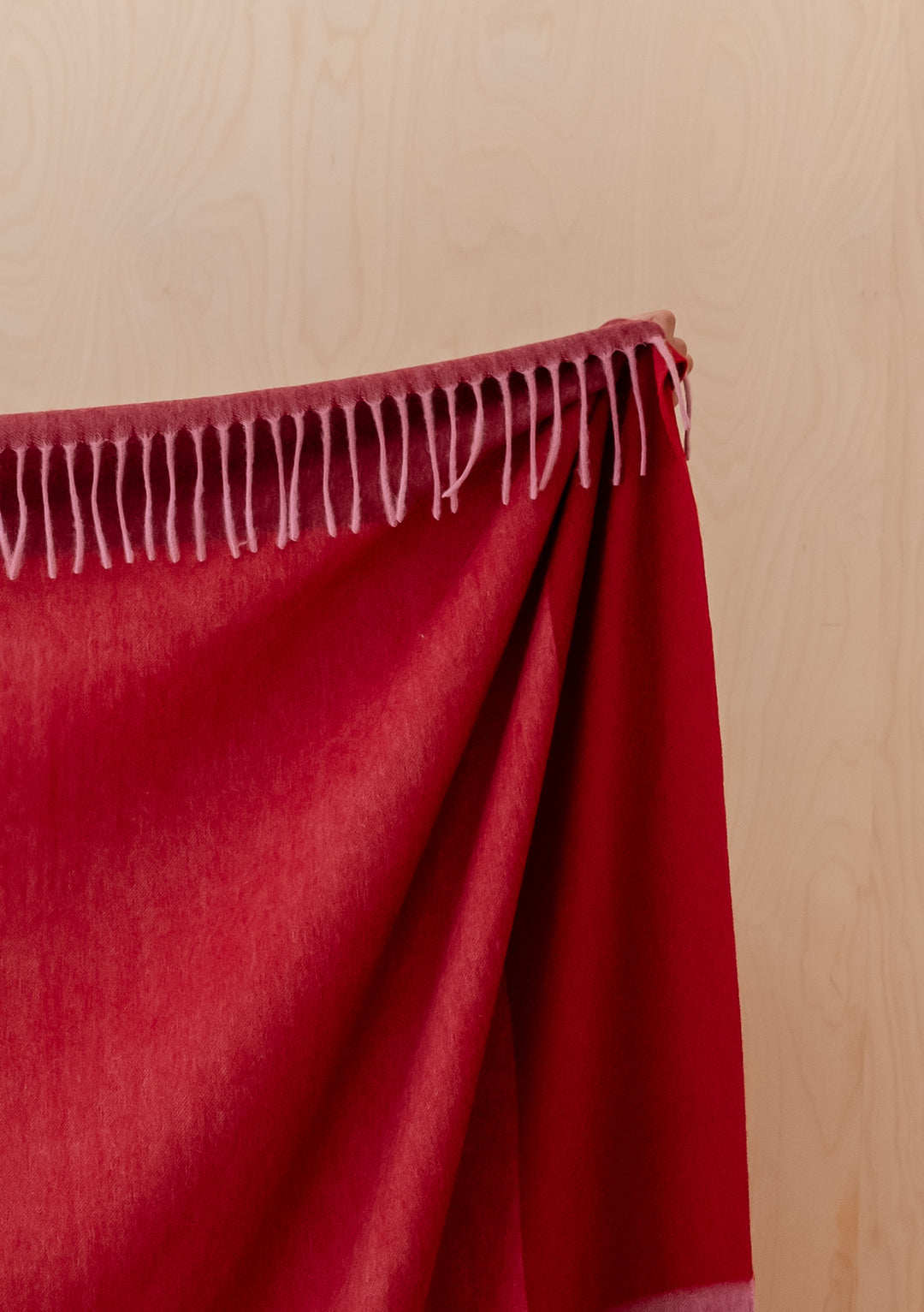 TBCo Lambswool Blanket in Berry Frame Check draped showing rich berry reds and soft fringed edges in natural light