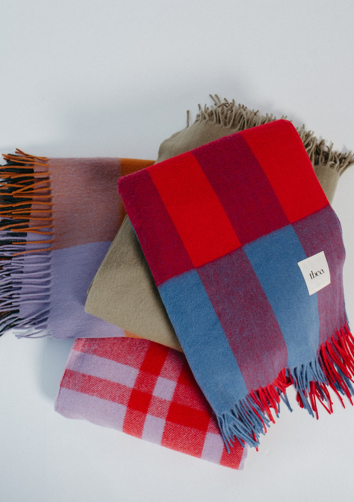 Lambswool Blanket in Red Modern Check by TBCo folded with fringed edges showing vibrant red and blue tones on soft wool fabric
