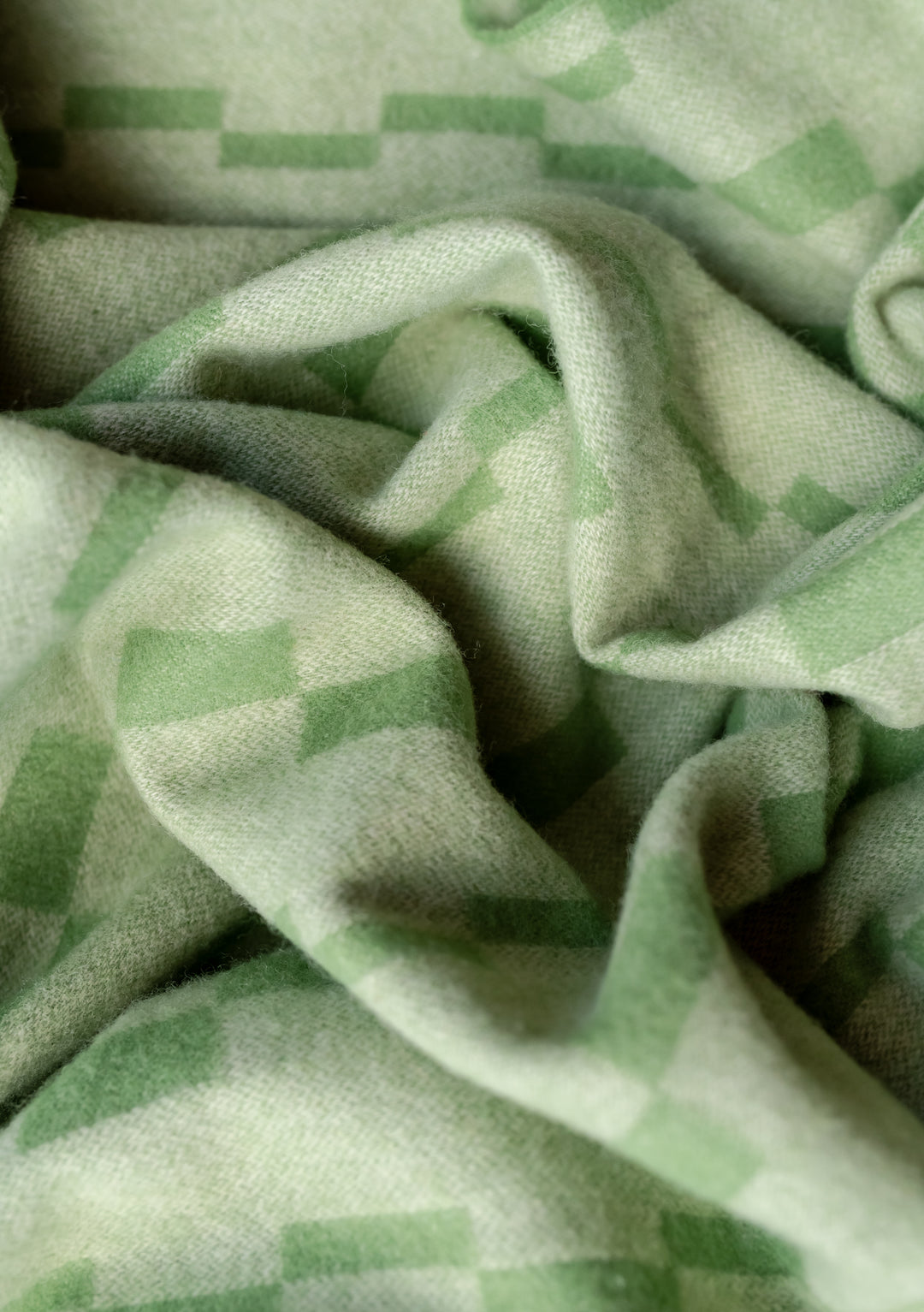 Close-up texture of TBCo Lambswool Blanket in Green Checker Stripe showing soft, folds and woven checkerboard pattern