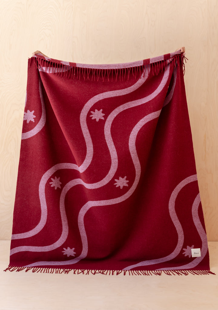 Lambswool Blanket in Red Wave Jacquard by TBCo draped showing fringed edges and pink wave pattern on red wool