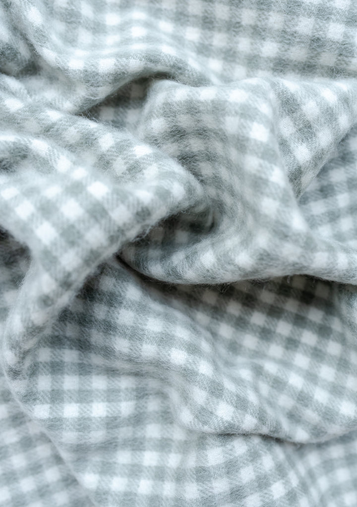 TBCo sage green and cream gingham lambswool baby blanket with soft folds showing micro check pattern texture and weave
