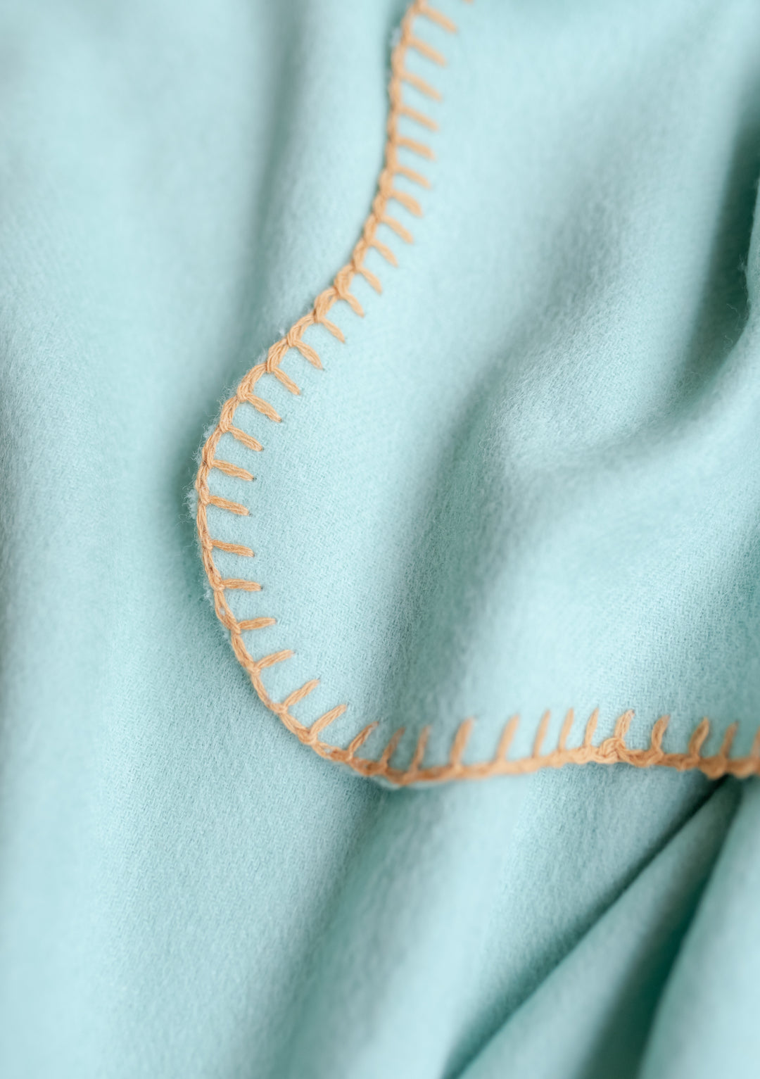 TBCo Lambswool Baby Blanket in mint green with tan scalloped edge stitching detail, showcasing soft wool texture and delicate finish