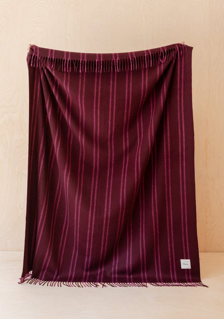 Lambswool Blanket in Wine Stripe by TBCo in dark burgundy with pink stripes and fringed edges displayed folded vertically