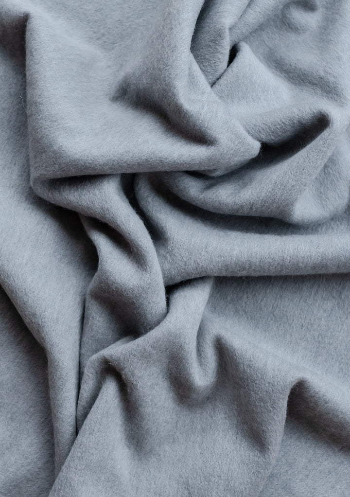 TBCo Lambswool Baby Blanket in Light Grey Melange showing soft, draped fabric texture with gentle folds and shadows