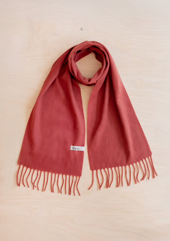 Lambswool Scarf in Mulberry by TBCo laid flat showing soft texture and fringed edges on light wood surface