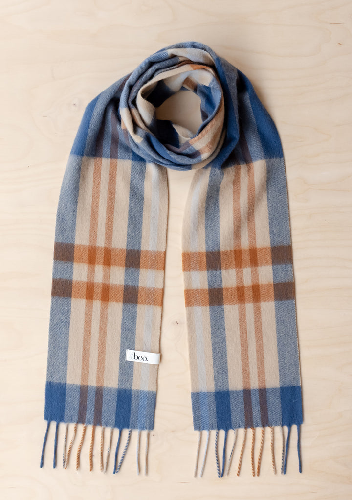 TBCo Lambswool Skinny Scarf in Camel Modern Tartan with blue and camel tartan pattern and fringed edges on wooden surface