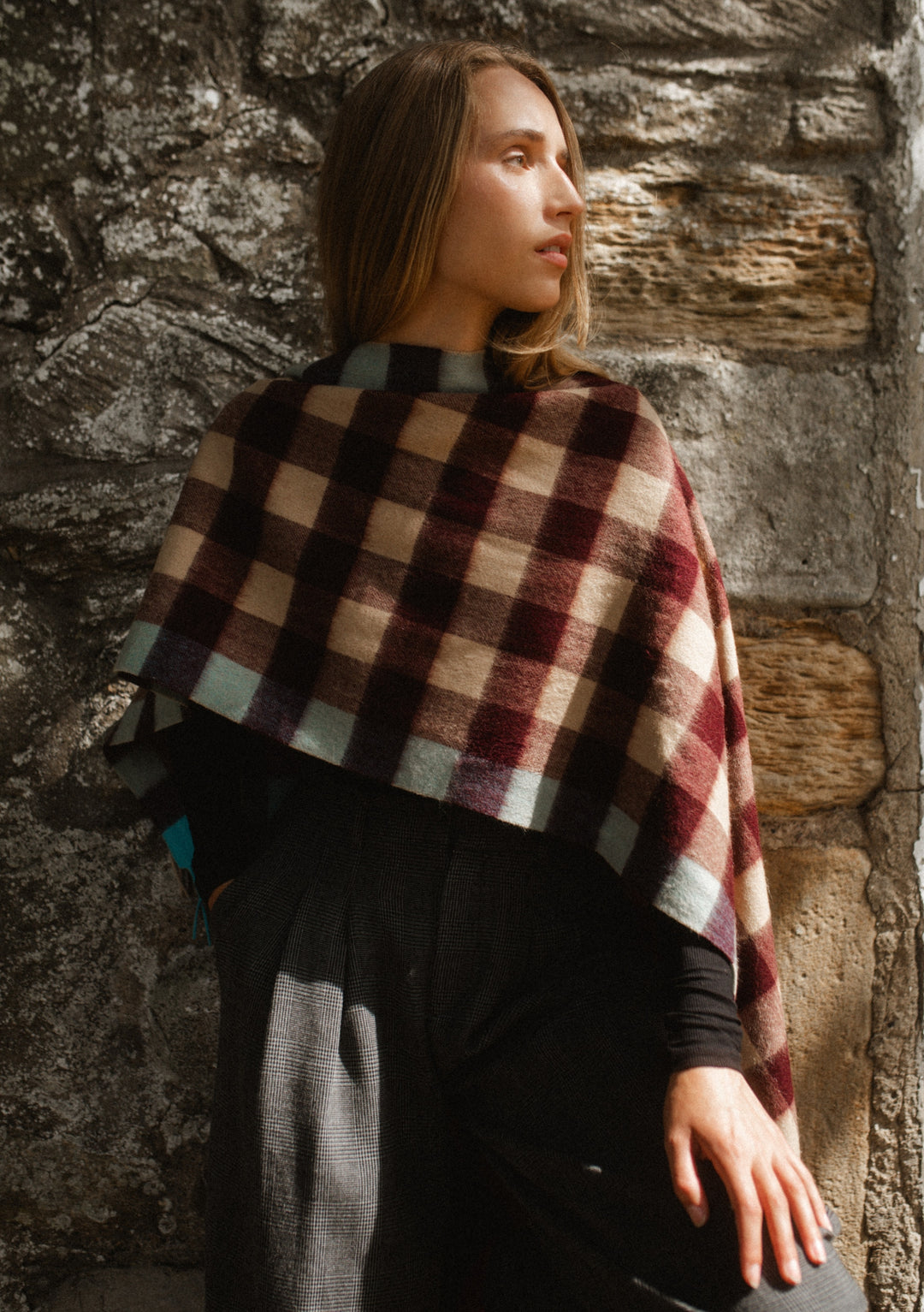 Woman wearing TBCo Lambswool Oversized Scarf in Camel Gingham with burgundy, camel and blue checks against stone wall