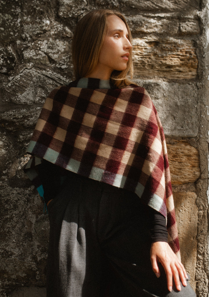 Woman wearing TBCo Lambswool Oversized Scarf in Camel Gingham with burgundy, camel and blue checks against stone wall