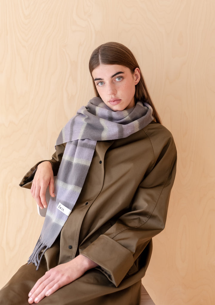 Woman wearing TBCo Lambswool Oversized Scarf in Charcoal Stripe with fringed edges and soft lilac grey tones