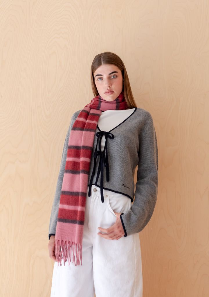 Model wearing TBCo Lambswool Oversized Scarf in Pink Stripe with fringes paired with grey cardigan and white trousers