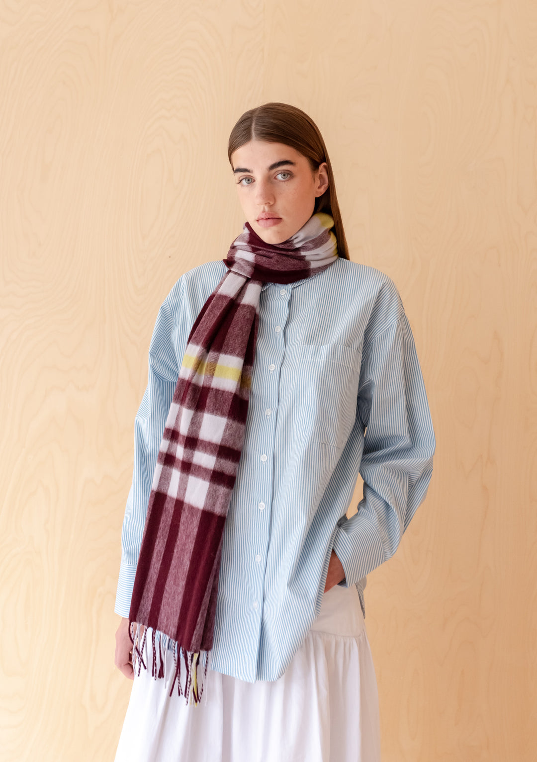 Model wearing TBCo Lambswool Oversized Scarf in Burgundy Modern Tartan styled with a light blue shirt and white skirt