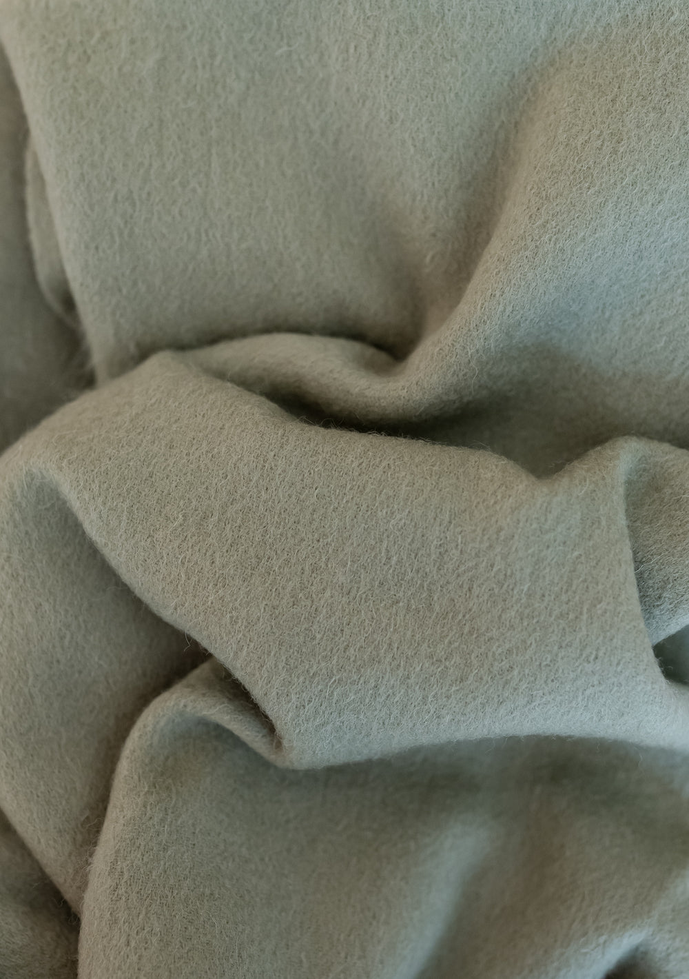 Close-up of the soft texture of TBCo Lambswool Blanket Scarf in Olive showcasing its premium quality lambswool fabric