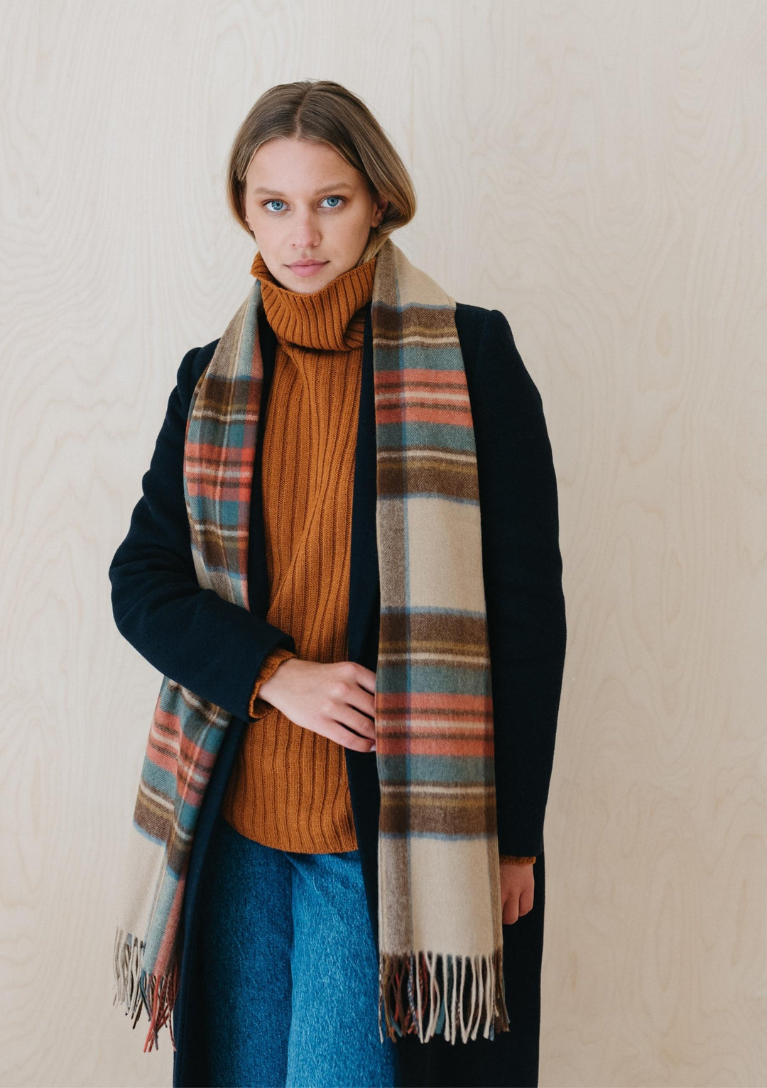 TBCo Stewart Dress Antique Tartan lambswool scarf styled with black coat and orange turtleneck, showing plaid pattern and fringe