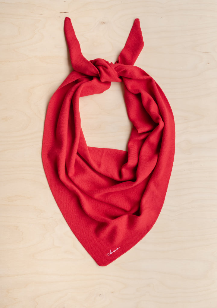 Large Merino Triangle Scarf in Red by TBCo, knitted from soft merino wool with embroidered logo on natural wood background