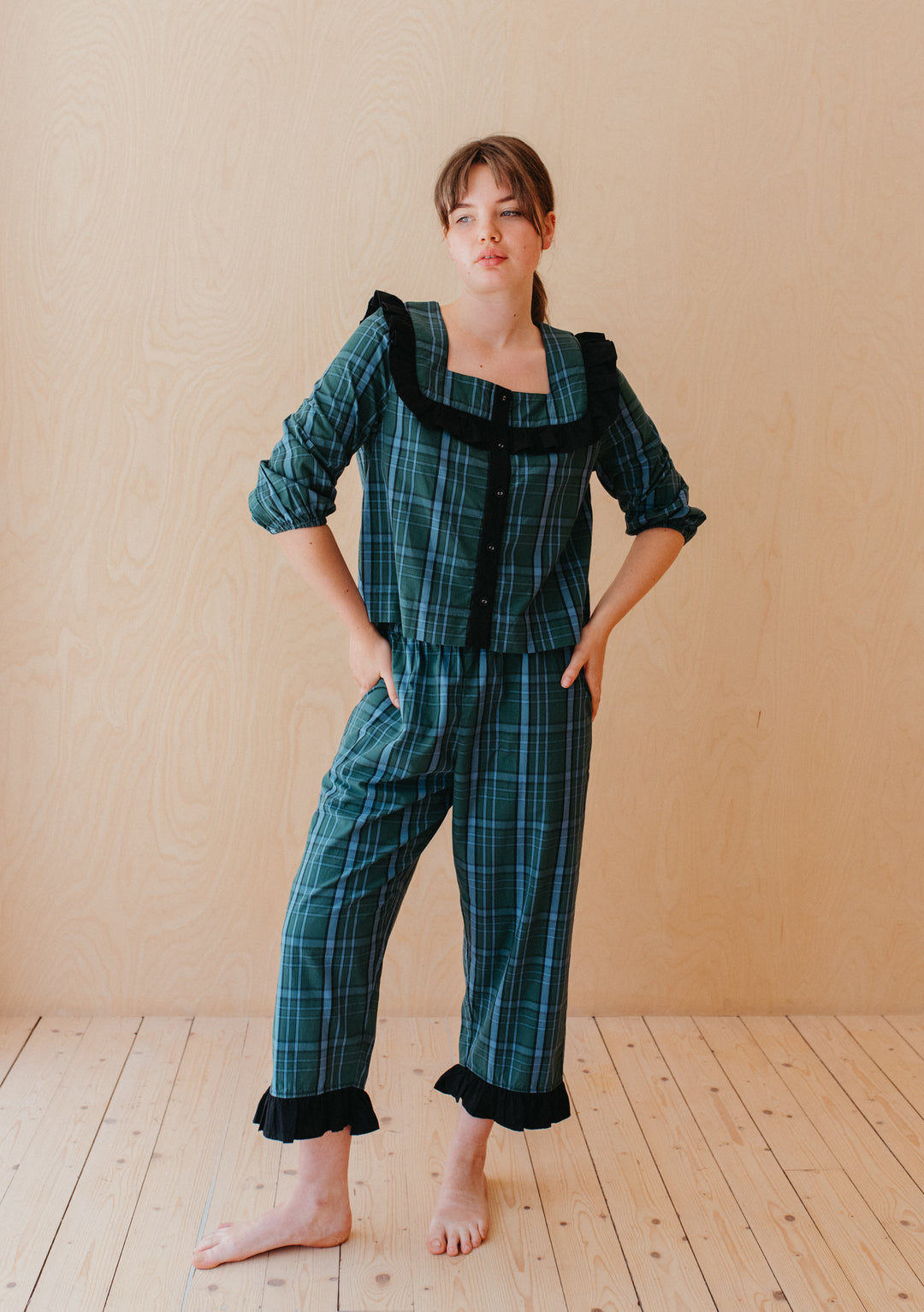 Woman wearing TBCo Cotton Pyjamas in Green Tartan with ruffle collar and cropped trousers standing barefoot