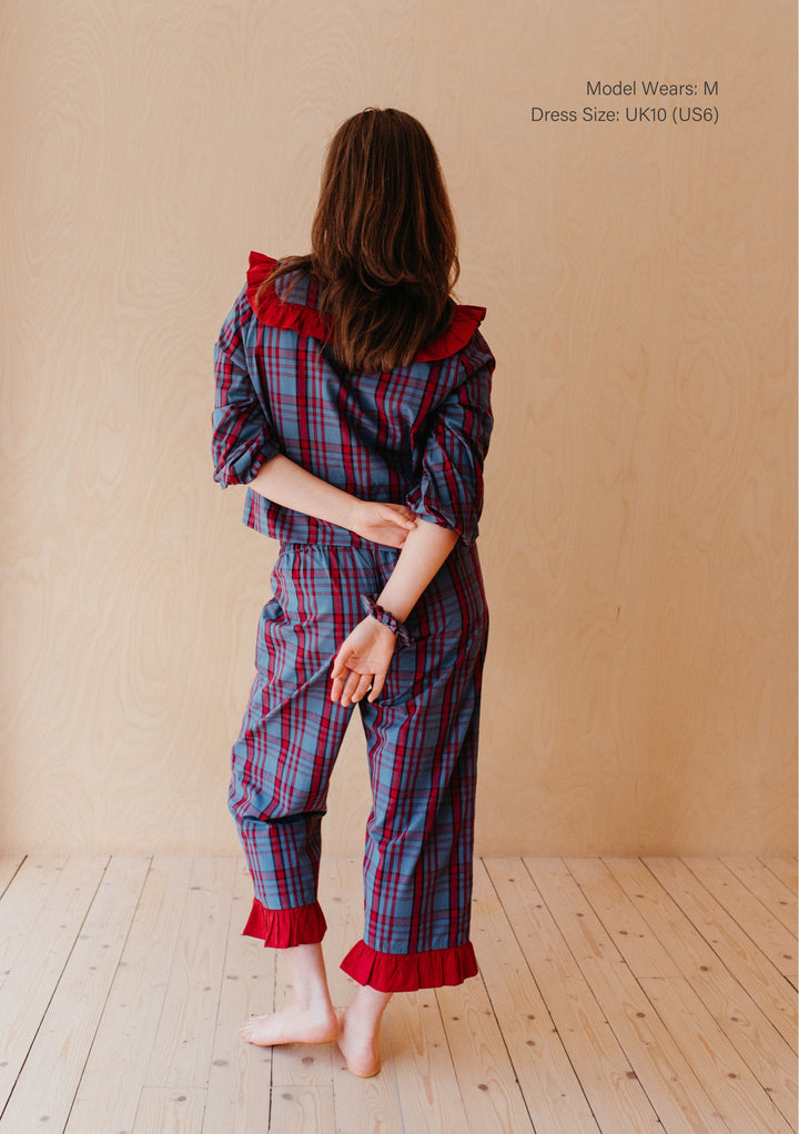 Back view of a woman wearing TBCo Cotton Pyjamas in Navy Tartan featuring ruffle collar and cropped trousers with frill details