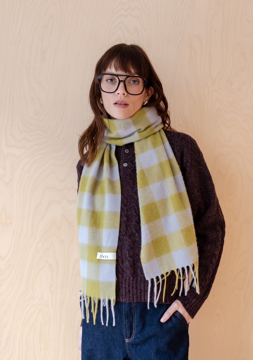 TBCo Lambswool Scarf in Avocado Gingham pattern showcasing soft green and blue checks with elegant fringing against wooden backdrop