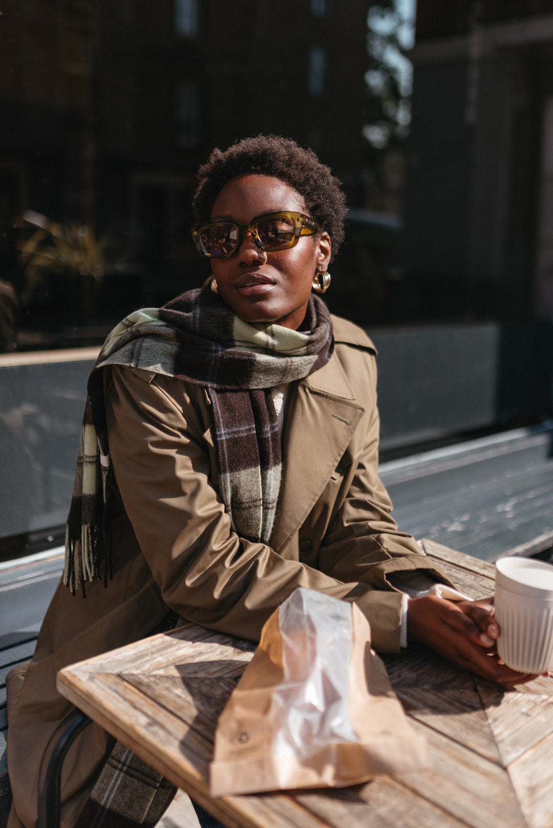 TBCo Lambswool Oversized Scarf in Mint Varsity Check styled with brown trench coat, shown draped in check pattern against outdoor cafe setting