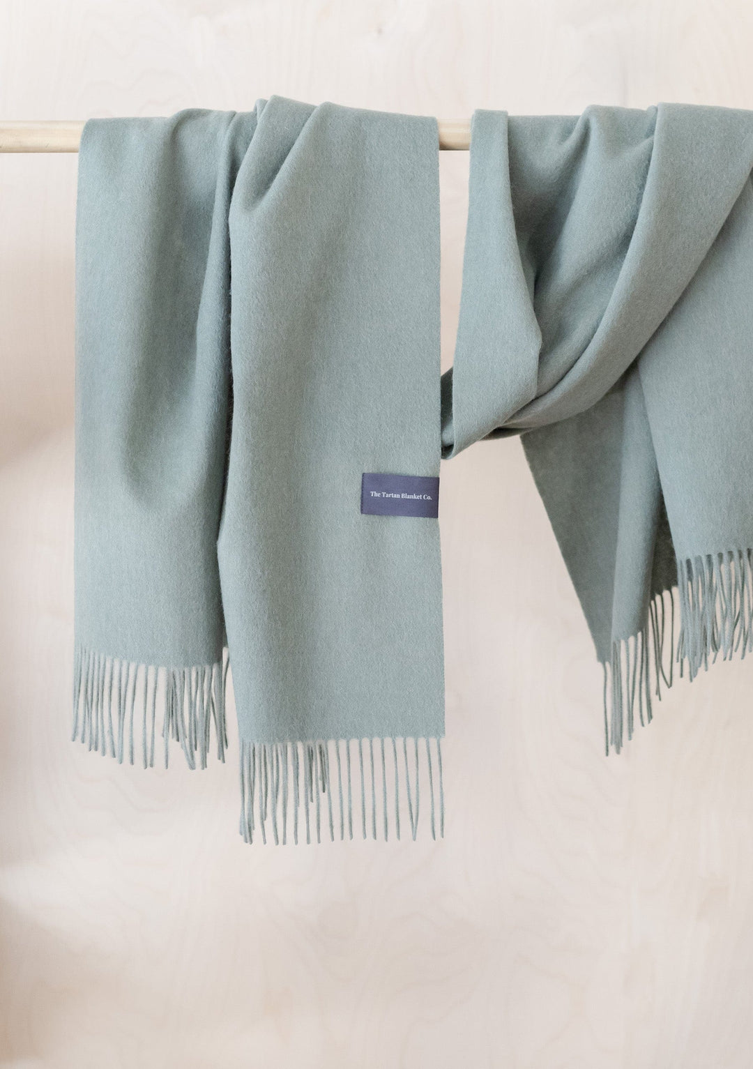 TBCo Lambswool Blanket Scarf in Sage Melange draped elegantly with fringed edges showing soft texture and luxurious drape