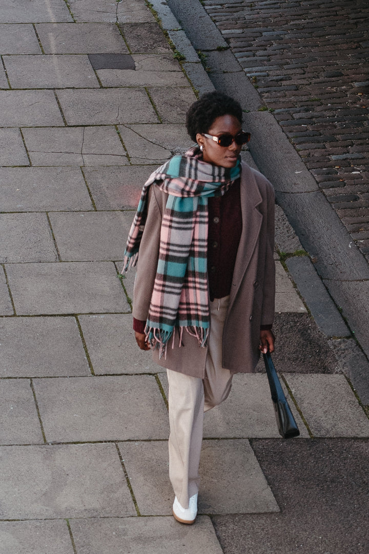 TBCo Lambswool Blanket Scarf in Green Tartan Check styled with beige coat and cream trousers on a cobblestone street