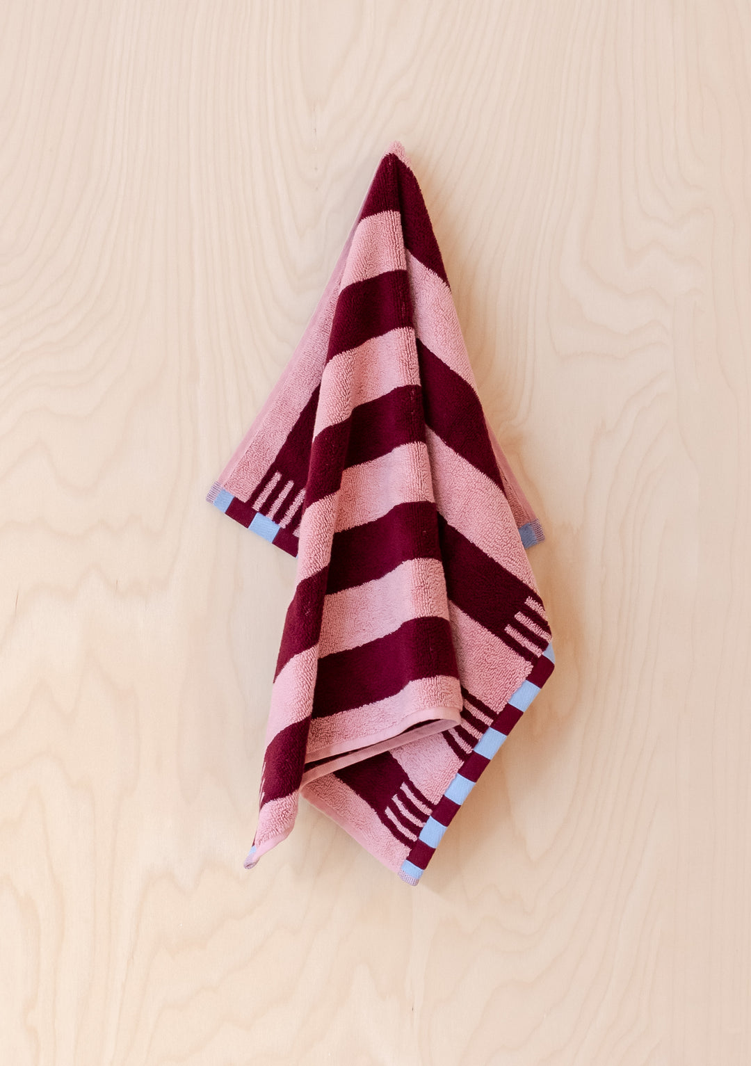 TBCo Cotton Towels in Pink Stripe with burgundy stripes and blue checkerboard trim, draped elegantly showing plush texture