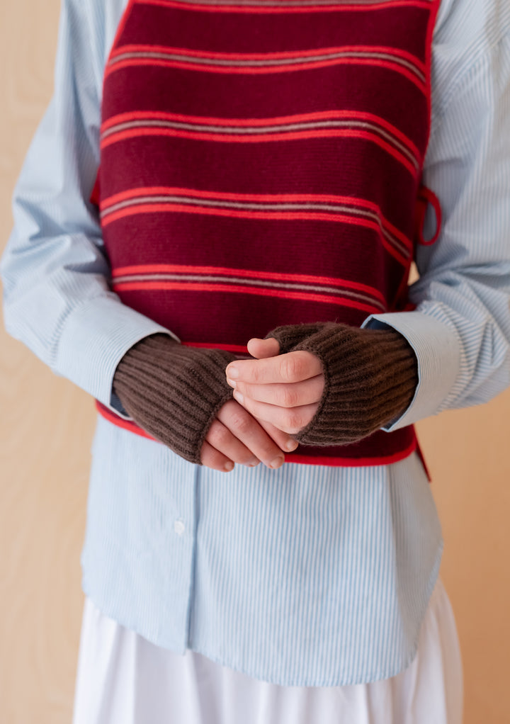 Hands wearing Cashmere & Merino Wrist Warmers in Brown by TBCo with layered striped vest and shirt outfit