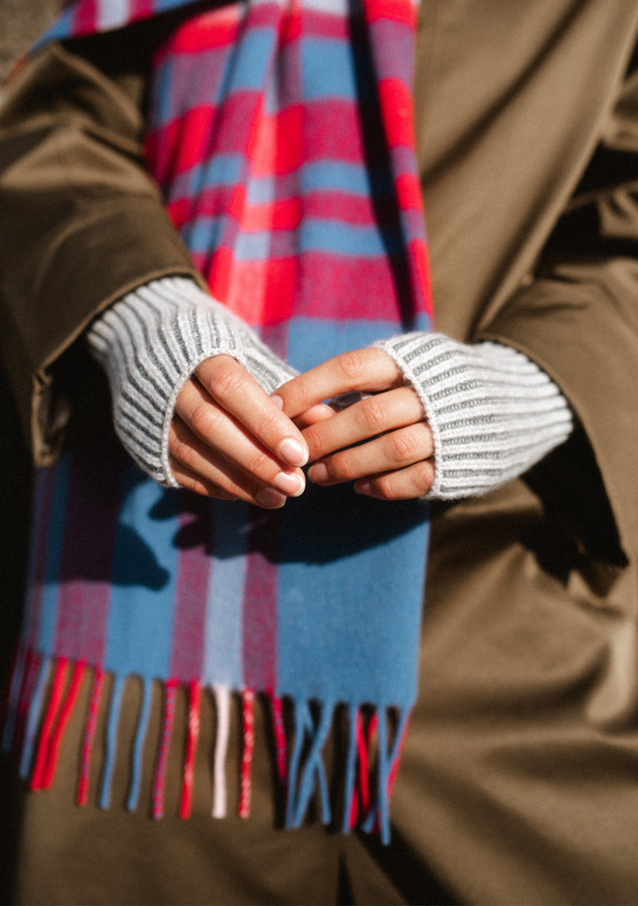 Hands wearing Cashmere & Merino Wrist Warmers in Charcoal Two-Tone by TBCo with a colorful scarf and coat.