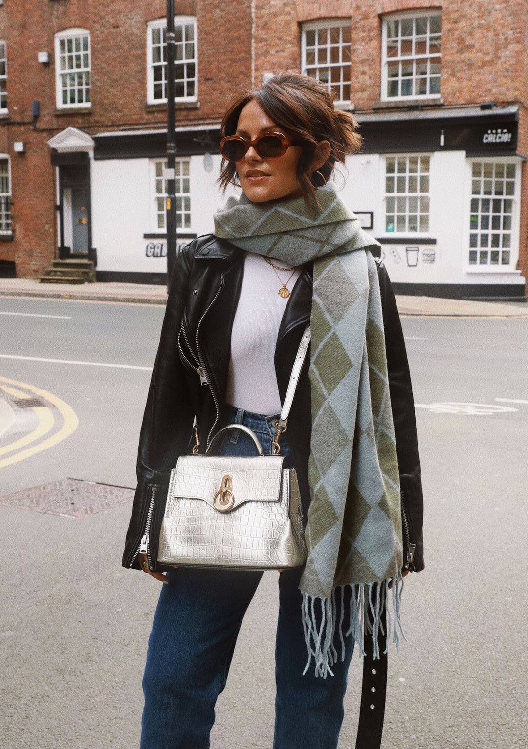 Soft grey and sage green TBCo x Amy Bell Dunnottar Scarf styled with leather jacket and jeans on a British street scene