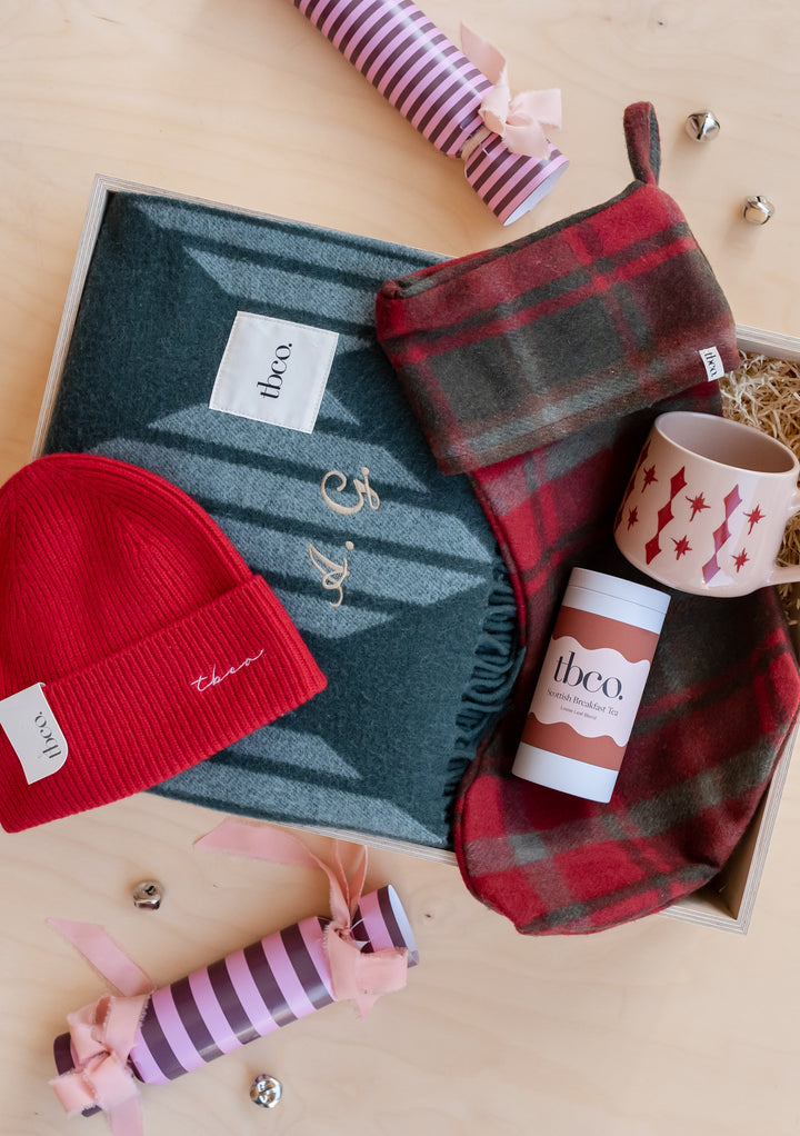 Build Your Own Christmas Gift Box by TBCo featuring a cosy blanket, red hat, tartan scarf and festive mug perfectly gift wrapped
