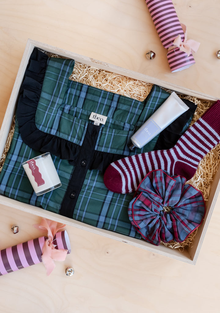 TBCo Pyjamas Gift Box featuring green checked pyjamas, striped socks, scrunchie, candle, and hand cream in wooden box
