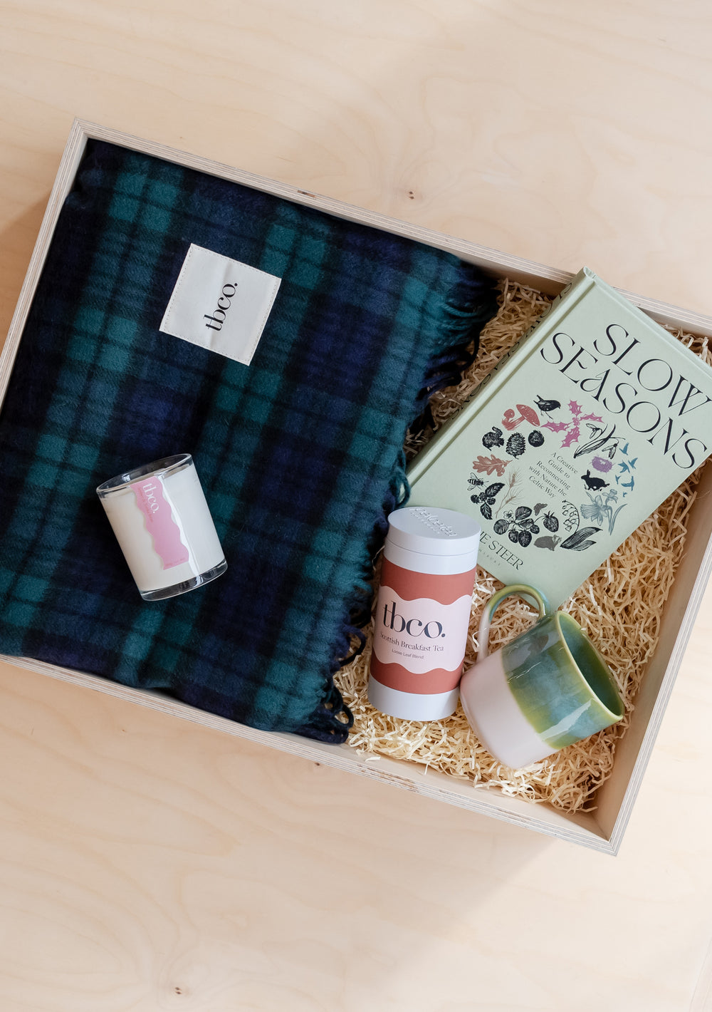 Build Your Own Tartan Gift Box by TBCo featuring a tartan blanket, candle, drink, ceramic mug, and a book in eco-friendly packaging.