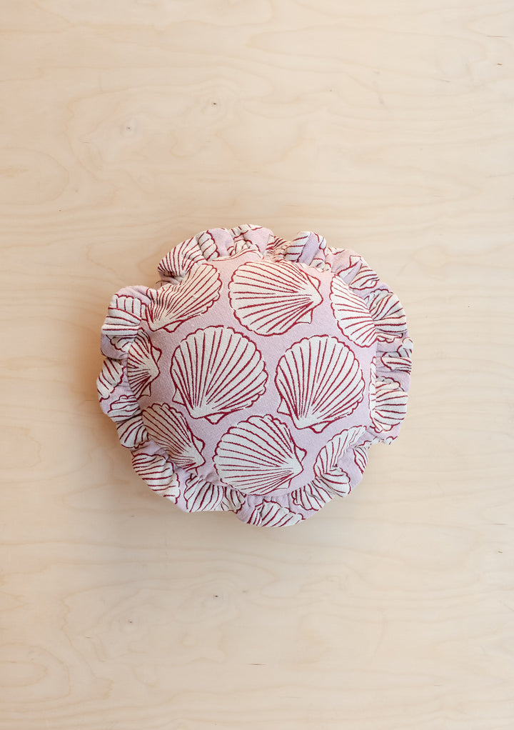 Portrait image of TBCo Cotton Cushion Cover in Pink Shell with ruffled edge and shell pattern on wooden background
