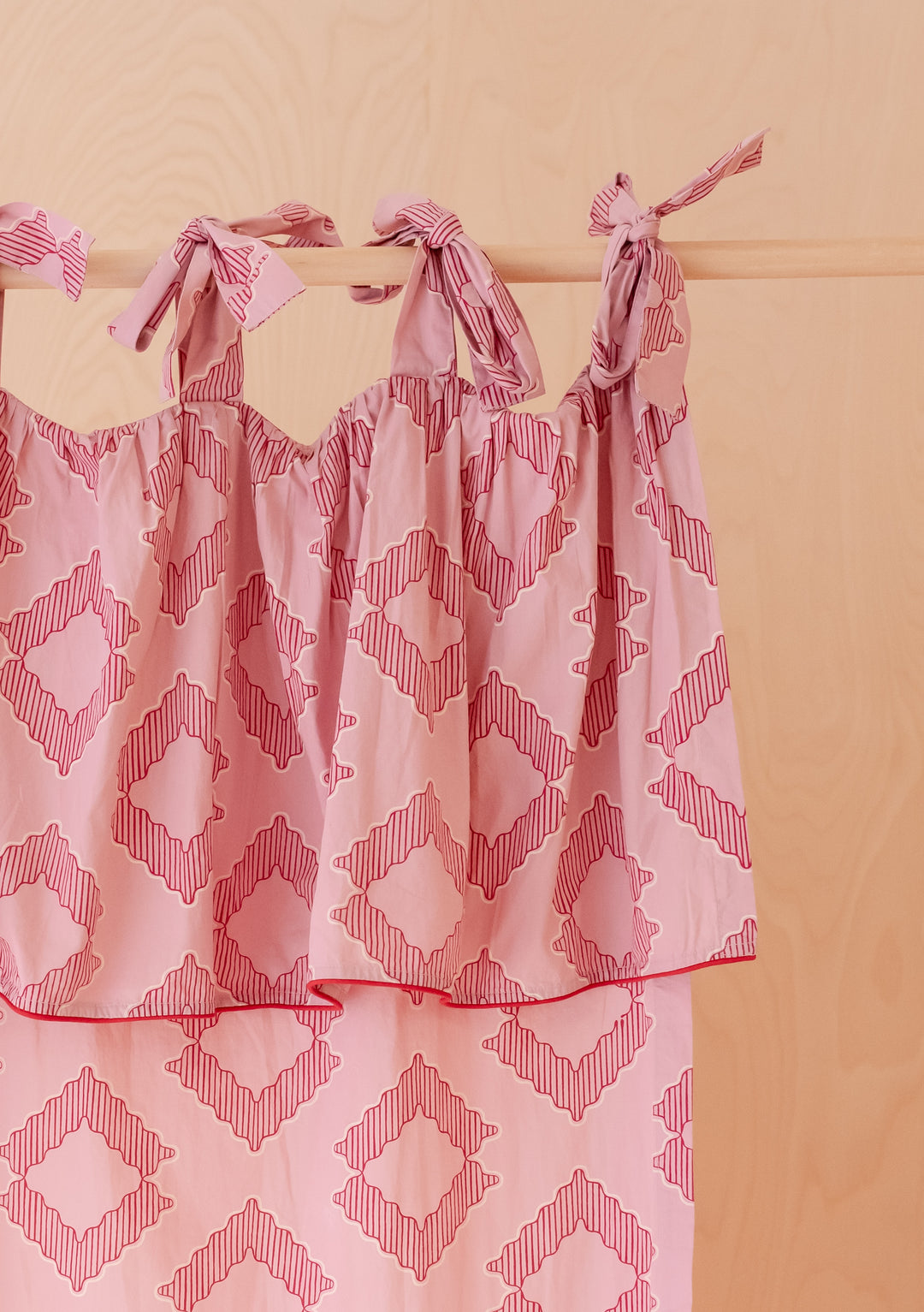 Pair of Cotton Tie-Top Curtains in Pink Diamond by TBCo, featuring soft pink fabric with geometric diamond pattern and tie-top details