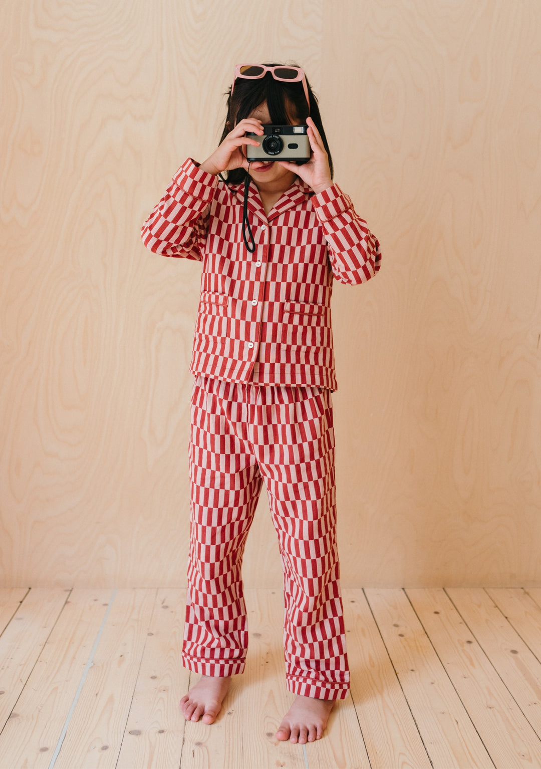 TBCo Cotton Kids Pyjamas in red and pink checkerboard pattern, featuring collared top and matching trousers with camera styling