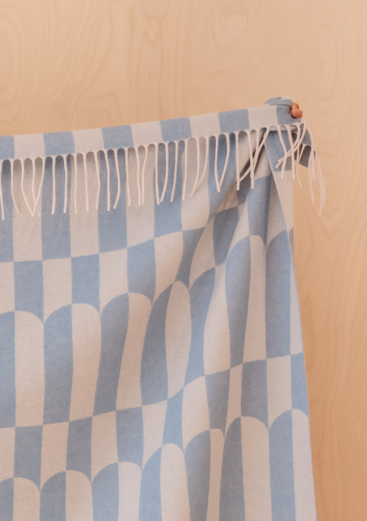 Portrait image of TBCo Lambswool Blanket in Blue Geo with fringed edge and light blue geometric pattern, gallery position 3.