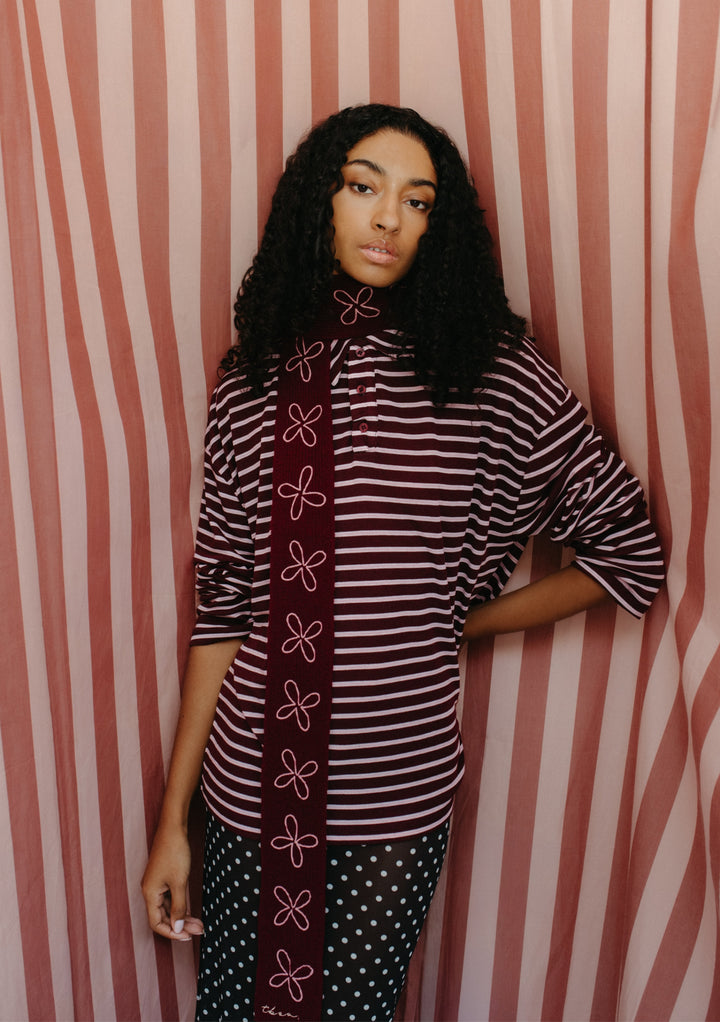 Model wearing TBCo Merino Wool Skinny Scarf in Burgundy Flora with pink floral embroidery and striped burgundy top