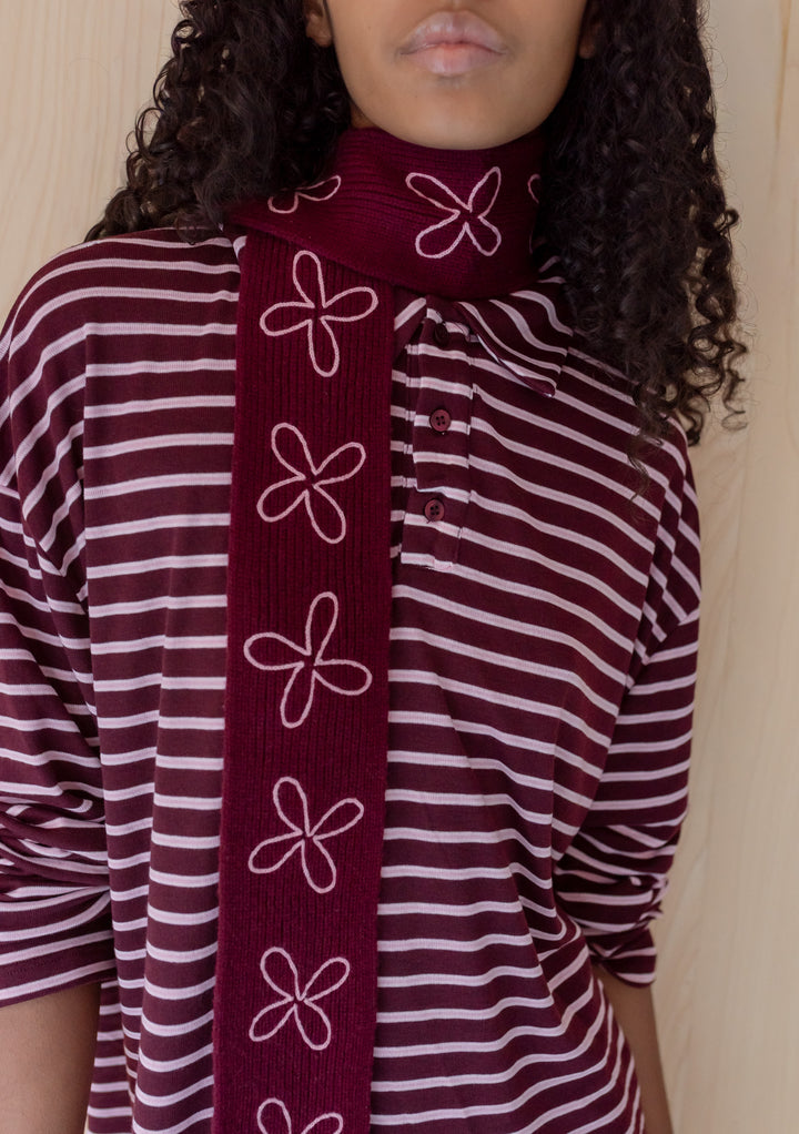 Close-up of TBCo Merino Wool Skinny Scarf in Burgundy Flora with pale pink floral embroidery worn over burgundy striped top