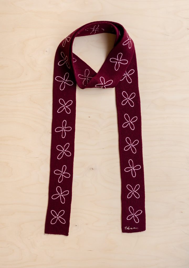 TBCo Merino Wool Skinny Scarf in Burgundy Flora with pale pink floral embroidery laid flat on light wood surface