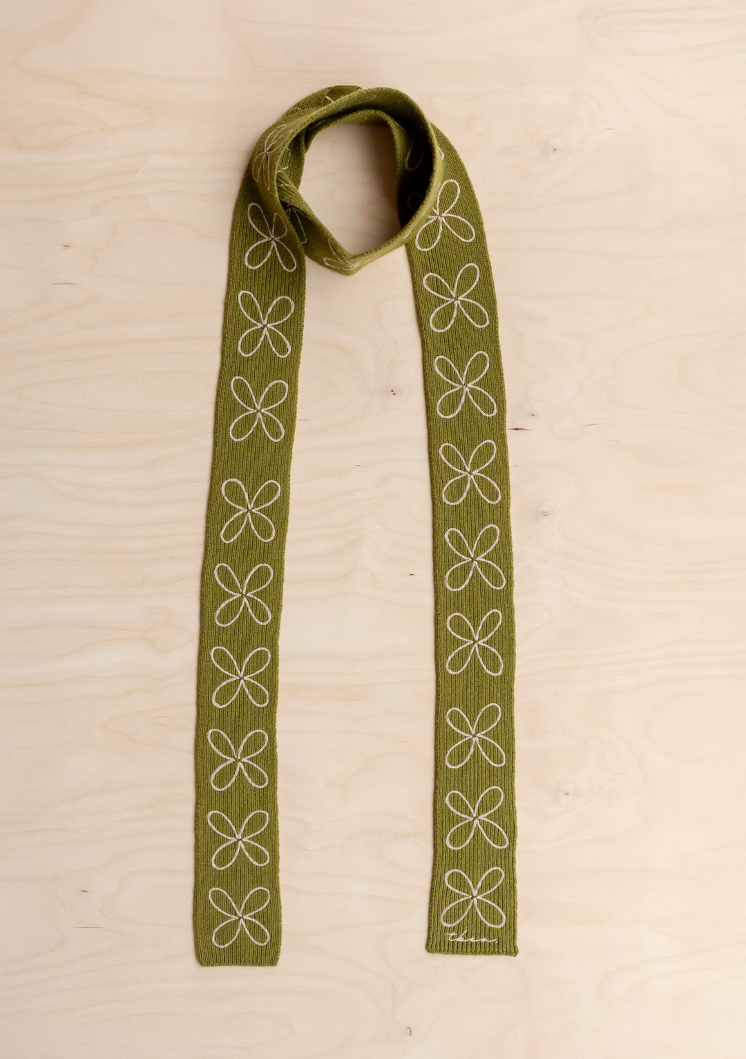 TBCo Merino Wool Skinny Scarf in Green Flora on a wooden background. 