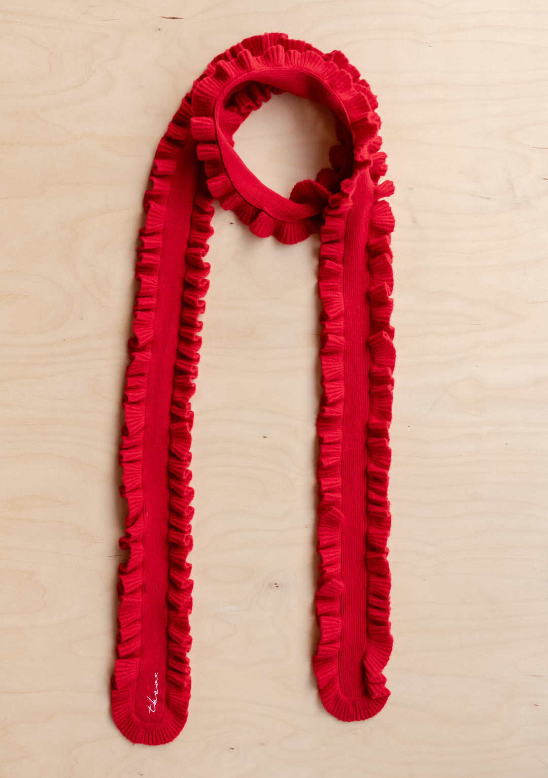 TBCo Merino Wool Skinny Scarf in Red Ruffle laid flat showing vibrant red colour and delicate ruffled trim on wooden surface