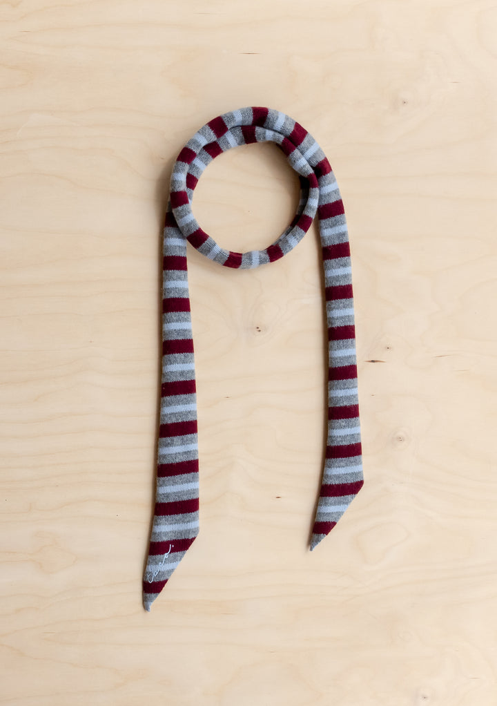 A TBCo Merino Wool Neck Tie in Burgundy Stripe lying flat on a wooden surface. 