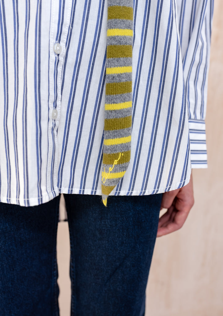 Close-up of Model wearing a TBCo Merino Wool Neck Tie in Green Stripe, styled over a blue stripe shirt and dark jeans