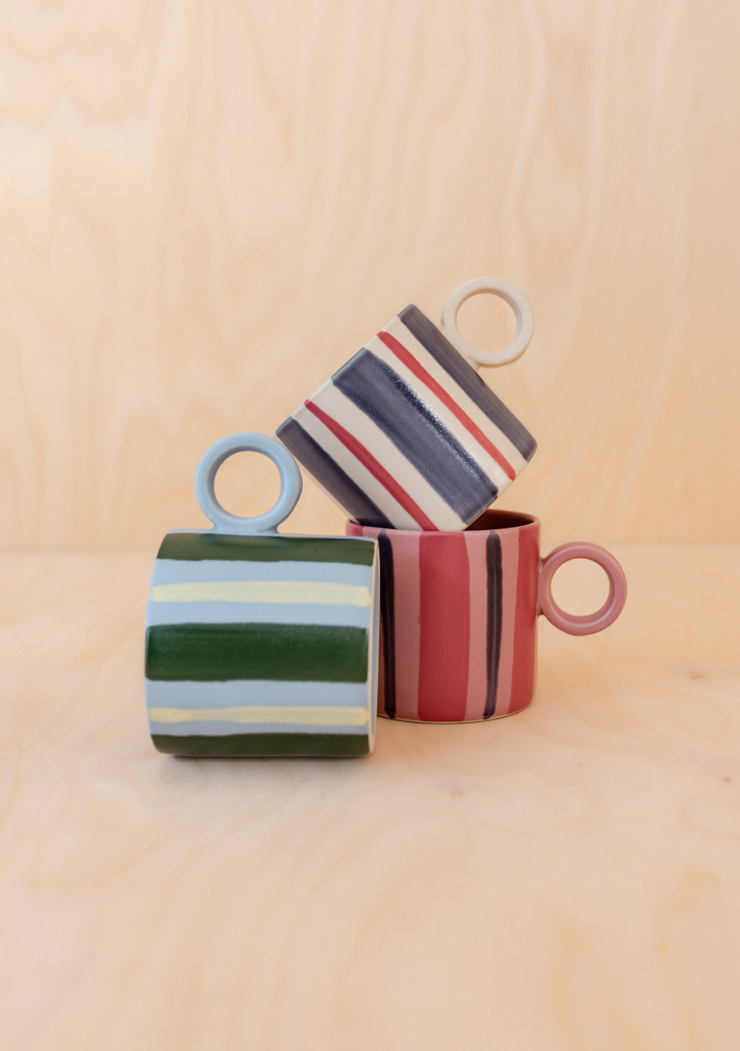 Three Blue Stripe Hand-Painted Mugs by TBCo stacked to display hand-painted colourful stripes on smooth ceramic surface