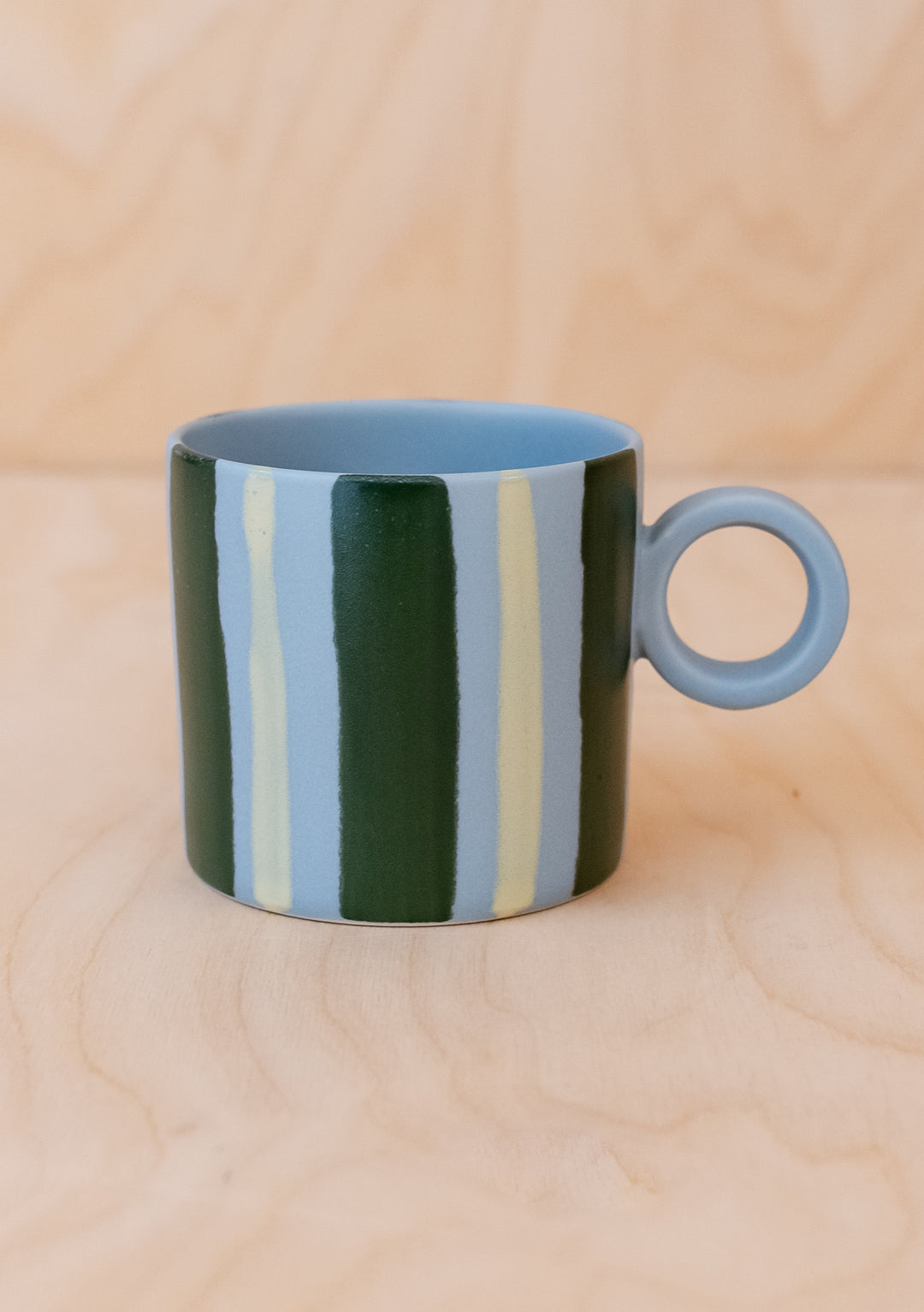 Green Stripe Hand-Painted Mug by TBCo, featuring bold green and pale blue stripes with a round handle on light wood surface