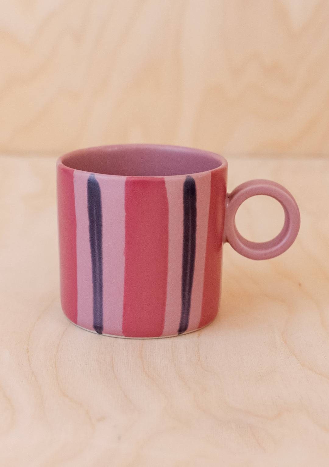 Pink Stripe Hand-Painted Mug by TBCo with soft pink and burgundy stripes and round handle on light wood surface