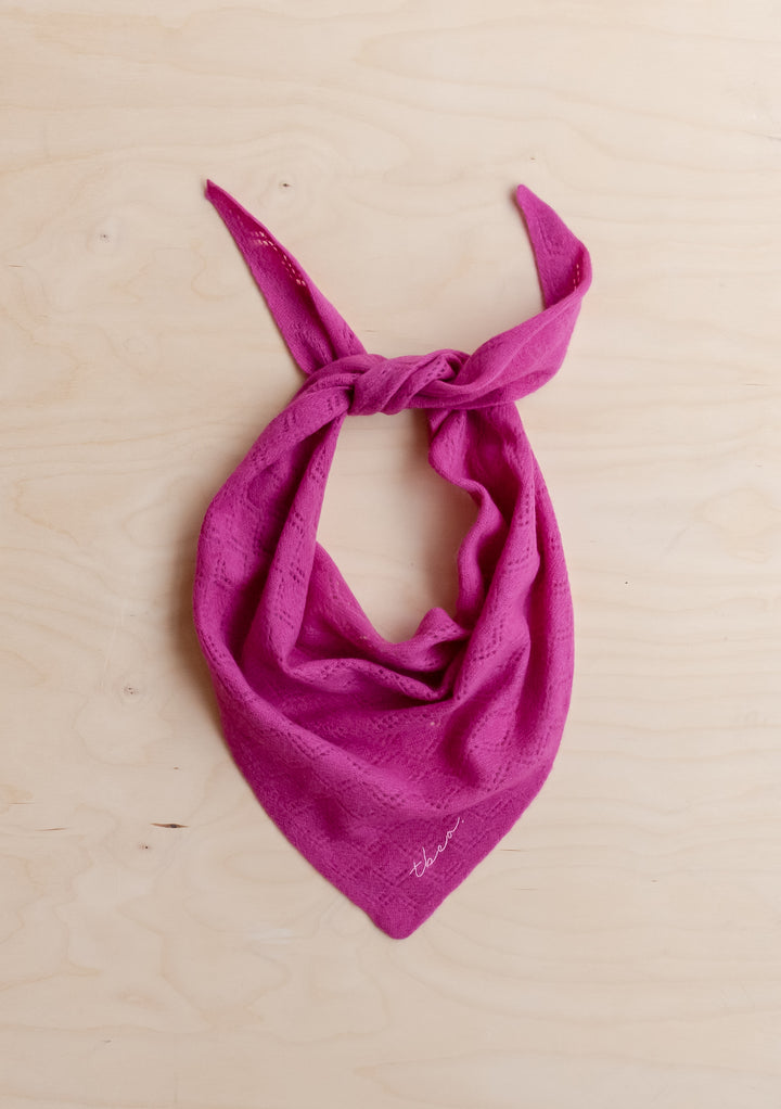 TBCo Merino Wool Triangle Scarf in Magenta Pointelle with delicate knit detail laid flat on light wood background
